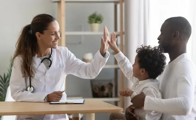 Family nurse practitioner high fiving pediatric patient in office during appointment